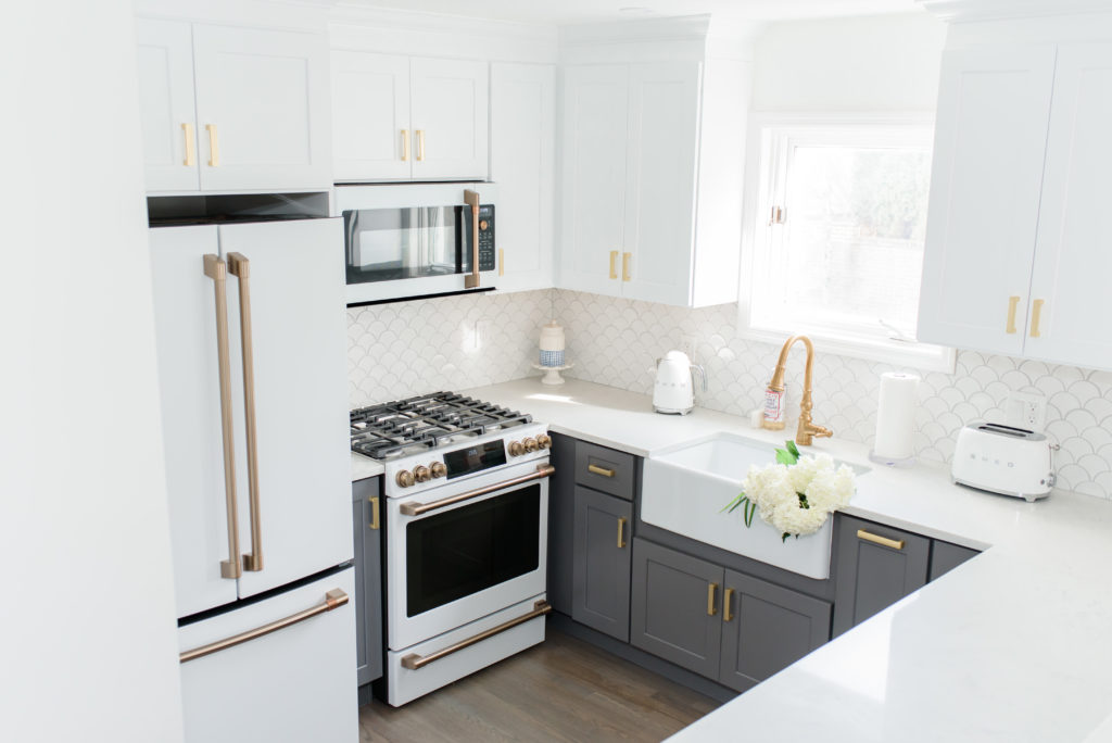 5 Things I Learned From My First Home Renovation. White and gold kitchen with charcoal lower cabinets and white upper cabinets. Two tone cabinets are so on trend right now! Includes farmhouse sink and cafe appliances. 